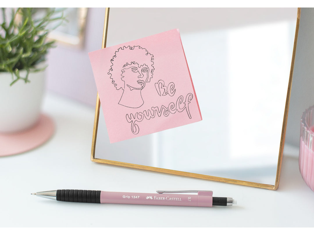 Faber-Castell Grip 1347 Mechanical Pencil 0.7mm in Rose Shadows displayed beside a mirror with a decorative note reading “Be yourself”, featuring a cushioned lead sleeve to reduce breakage, non-slip rubber grip zone, retractable lead mechanism and extra-long twist-out eraser for writing, journaling, sketching and everyday study.
