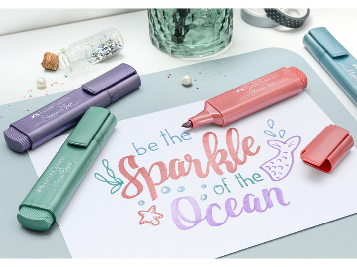 Faber-Castell Textliner 46 Metallic Highlighters being used to create decorative hand lettering and artwork, featuring metallic highlighters in red, violet, green and blue shades with shimmering metallic ink effects on light paper for journaling, card making and creative projects.