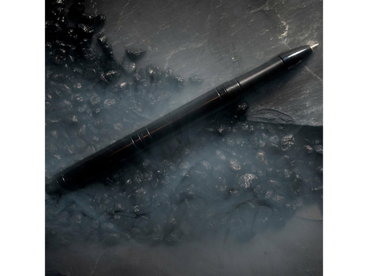 Fisher Space Pen Backpacker black pen on dark textured surface with mist effect showing rugged outdoor design