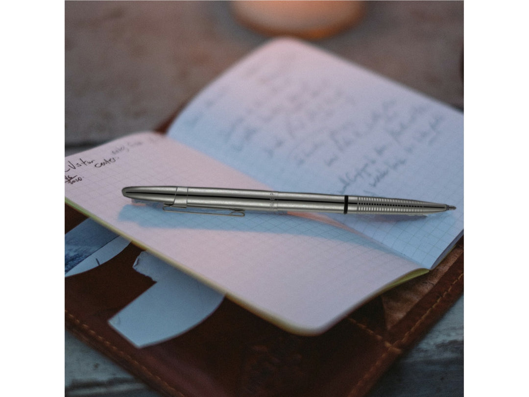 Fisher Space Pen Bullet chrome pen with clip resting on open notebook with handwritten notes