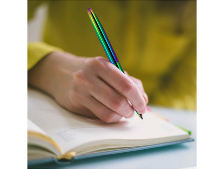Fisher Space Pen Bullet rainbow pen used for writing in notebook showing iridescent colour shift finish