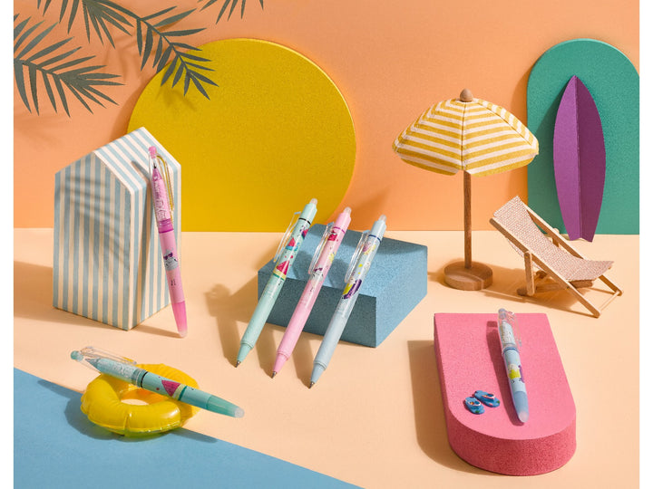 Pilot FriXion Pool Party Edition erasable pens featuring Sunny, Bubbly and Frosty designs displayed in a colourful poolside scene with parasol, deckchair and surfboard