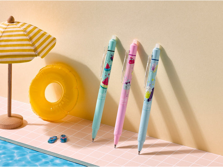 Pilot FriXion Clicker 0.7 Pool Party Edition pens in three colourful summer designs displayed beside a miniature parasol and inflatable pool ring