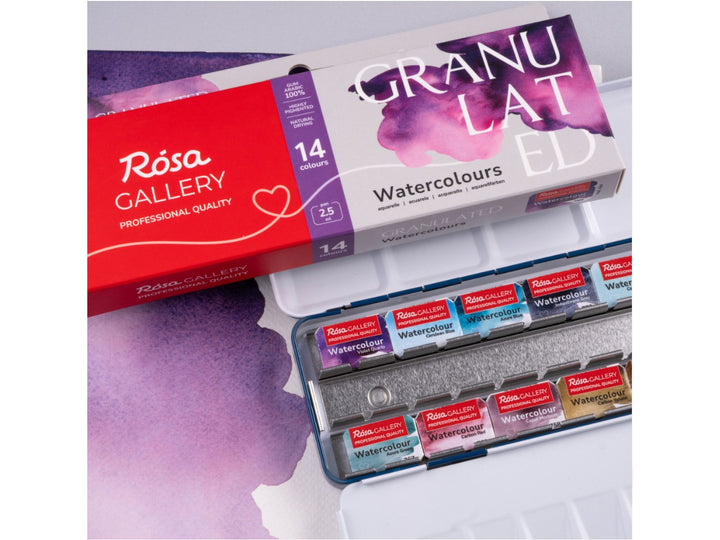 Lifestyle image of the ROSA Gallery Granulated Watercolour Set featuring updated Granulated Collection packaging, a metal watercolour case with 14 professional granulating watercolour pans, integrated mixing palette and textured granulated effects designed for expressive watercolour painting and atmospheric artwork