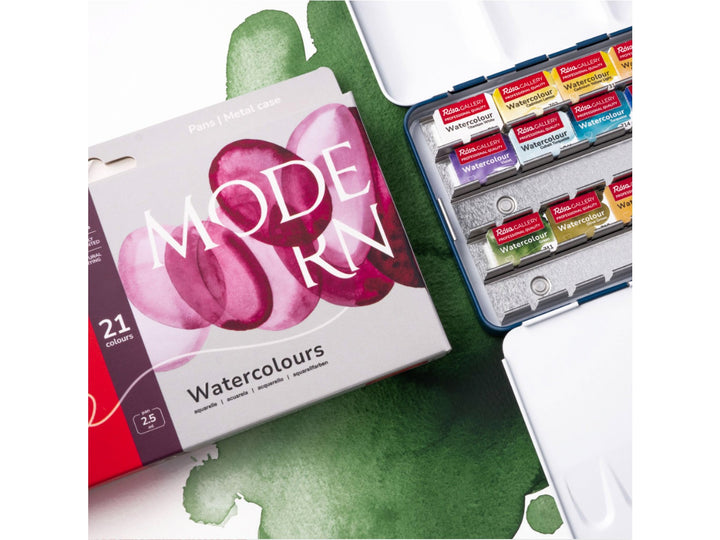 Lifestyle image of the ROSA Gallery Modern Watercolour Set featuring updated Modern Collection packaging alongside an open metal watercolour case filled with 21 professional watercolour half pans. The image showcases vibrant green watercolour washes, integrated mixing palette surfaces and a contemporary colour selection developed for illustration, urban sketching and modern watercolour painting