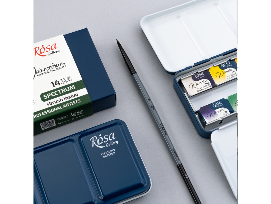 Lifestyle image of the ROSA Gallery Spectrum Watercolour Set featuring updated Spectrum Collection packaging, an included travel brush, open metal watercolour case with professional watercolour pans and integrated mixing palette, showcasing a portable all-in-one painting set designed for watercolour painting, sketching and creative work on the go