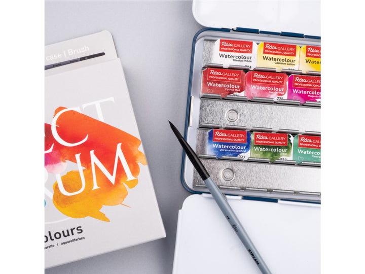 Close-up of the ROSA Gallery Spectrum Watercolour Set featuring updated Spectrum Collection packaging, an included travel watercolour brush and an open metal watercolour case with 21 professional watercolour half pans. The image highlights the integrated mixing palette and versatile colour selection designed for watercolour painting, illustration, urban sketching and creative colour mixing