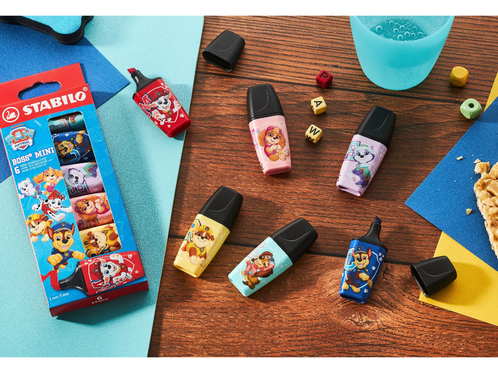STABILO BOSS MINI PAW Patrol highlighters in six bright colours featuring Chase, Marshall, Skye, Rubble, Everest and Liberty designs, displayed with the Wallet of 6 packaging in a colourful desk setting