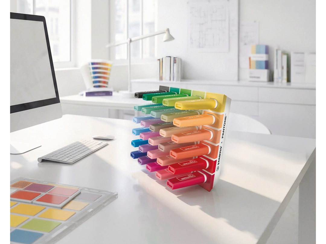 STABILO BOSS ORIGINAL x PANTONE desk set of 30 highlighters displayed upright on a white desk in a bright modern workspace, showing the full spectrum of colours