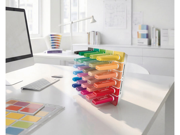 STABILO BOSS ORIGINAL x PANTONE desk set of 30 highlighters displayed upright on a white desk in a bright modern workspace, showing the full spectrum of colours