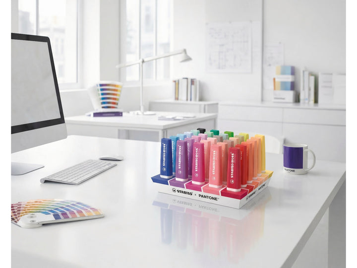 STABILO BOSS ORIGINAL x PANTONE desk set of 30 assorted highlighters displayed flat on a white desk in a bright modern workspace with colour swatches and a PANTONE mug