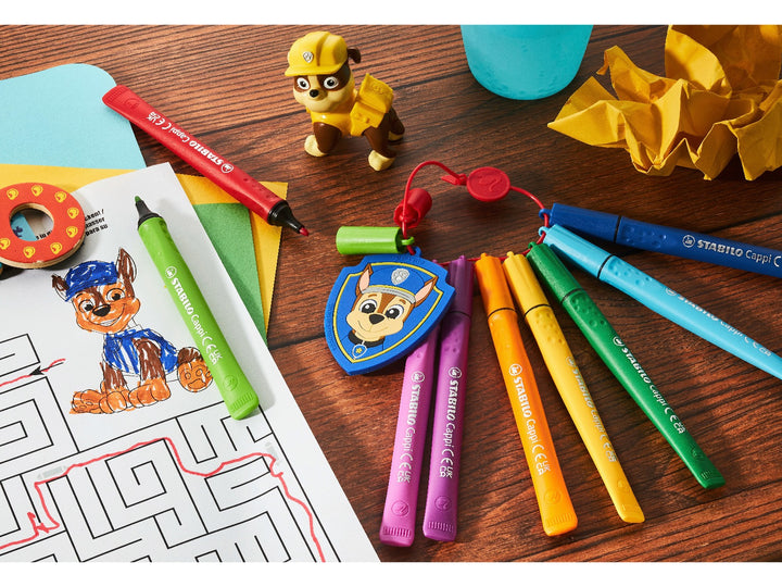 STABILO Cappi PAW Patrol felt-tip pens attached to the cap ring with Chase police badge, displayed beside a PAW Patrol colouring activity on a wooden craft table