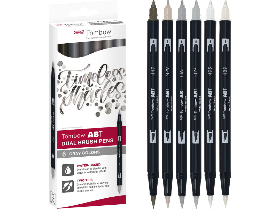 Tombow ABT Dual Brush Pen Grey Colours Set of 6 featuring Warm Grey 8 (N49), Cool Grey 5 (N65), Cool Grey 3 (N75), Warm Grey 2 (N79), Warm Grey 1 (N89) and Cool Grey 8 (N95), displayed alongside the original retail packaging with dual brush and fine tips for sketching, shading, hand lettering, illustration and monochrome artwork.