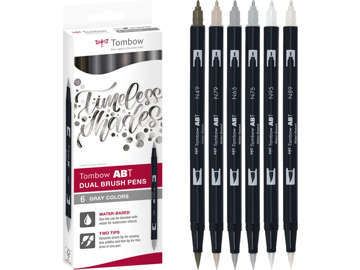 Tombow ABT Dual Brush Pen Grey Colours Set of 6 featuring Warm Grey 8 (N49), Cool Grey 5 (N65), Cool Grey 3 (N75), Warm Grey 2 (N79), Warm Grey 1 (N89) and Cool Grey 8 (N95), displayed alongside the original retail packaging with dual brush and fine tips for sketching, shading, hand lettering, illustration and monochrome artwork.