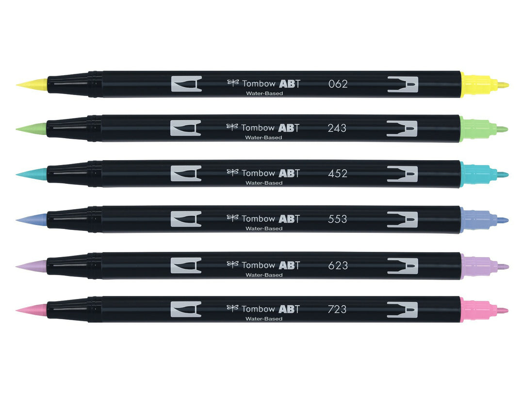 Tombow ABT Dual Brush Pen Pastel Colours Set of 6 displayed individually, featuring Pale Yellow (062), Mint (243), Process Blue (452), Mist Purple (553), Purple Sage (623) and Pink (723), each with dual brush and fine tips visible for hand lettering, colouring, journaling, illustration and watercolour-style effects.