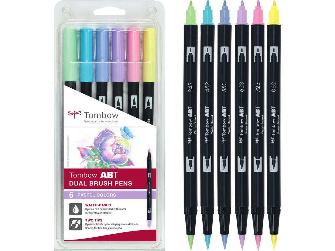 Tombow ABT Dual Brush Pen Pastel Colours Set of 6 featuring Pale Yellow (062), Mint (243), Process Blue (452), Mist Purple (553), Purple Sage (623) and Pink (723), displayed alongside the original retail packaging with dual brush and fine tips for hand lettering, colouring, journaling and illustration.