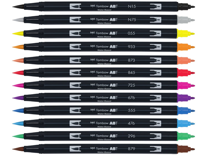 Tombow ABT Dual Brush Pen Primary Colours Set of 12 displayed individually, featuring Black (N15), Cool Grey 3 (N75), Process Yellow (055), Orange (933), Coral (873), Carmine (845), Rhodamine Red (725), Royal Purple (676), Ultramarine (555), Cyan (476), Green (296) and Brown (879), each with dual brush and fine tips visible.