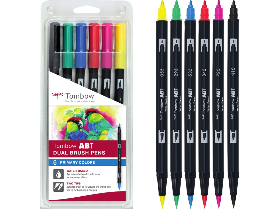 Tombow ABT Dual Brush Pen Primary Colours Set of 6 blister pack featuring Black (N15), Process Yellow (055), Green (296), Cobalt Blue (535), Rhodamine Red (725) and Carmine (845), displayed alongside the original retail packaging with dual brush and fine tips for hand lettering, colouring, illustration and creative projects.
