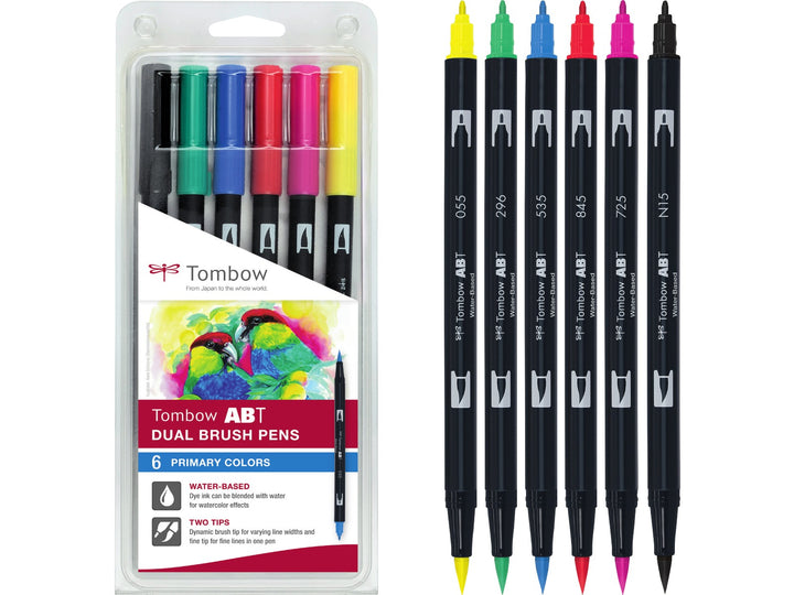 Tombow ABT Dual Brush Pen Primary Colours Set of 6 blister pack featuring Black (N15), Process Yellow (055), Green (296), Cobalt Blue (535), Rhodamine Red (725) and Carmine (845), displayed alongside the original retail packaging with dual brush and fine tips for hand lettering, colouring, illustration and creative projects.