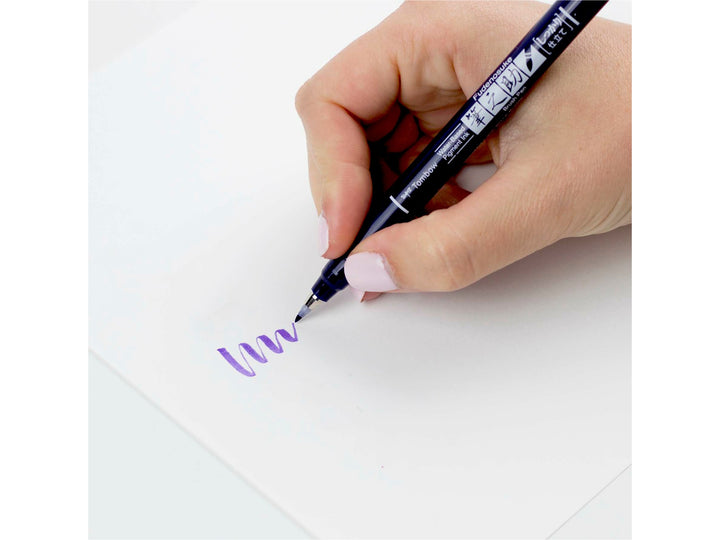 Tombow Fudenosuke purple brush pen being used to create variable line widths, demonstrating the firm elastic brush tip and water-based pigment ink for hand lettering and illustration