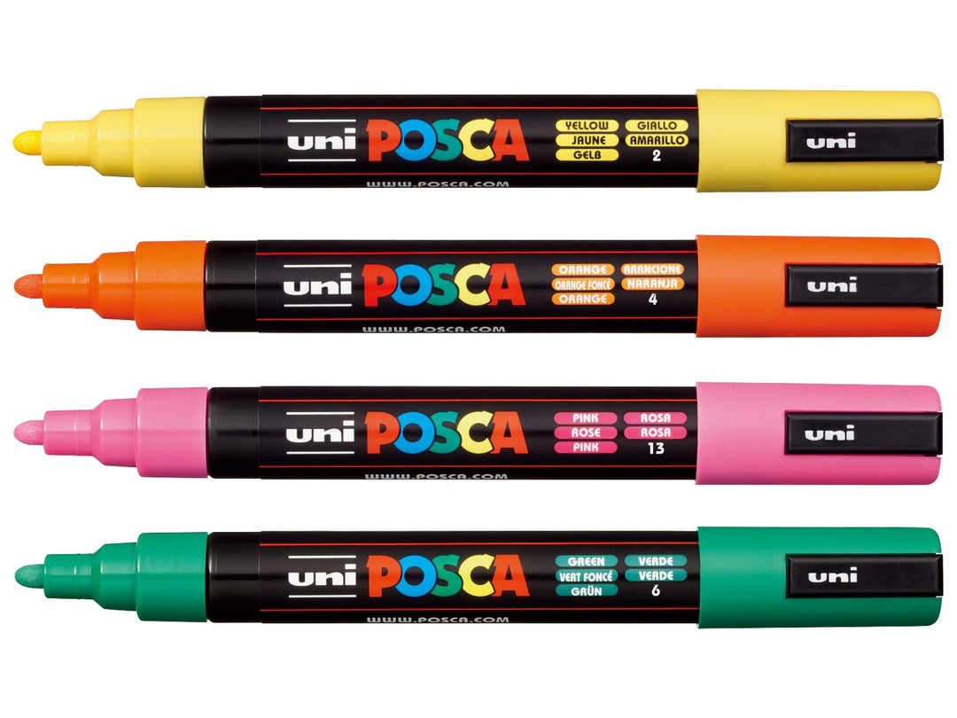 Four uni POSCA PC-5M paint markers shown uncapped in Yellow, Orange, Pink and Green, arranged together on a white background