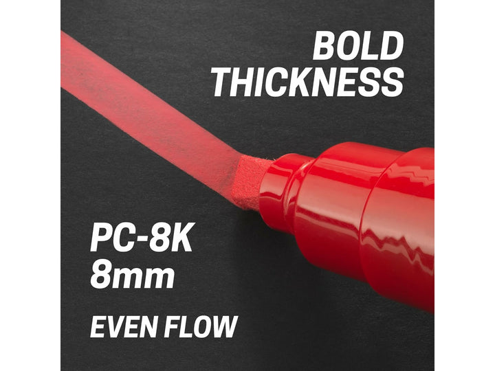 Red uni POSCA PC-8K paint marker applying a bold, even line with its broad 8mm chisel tip on a black surface